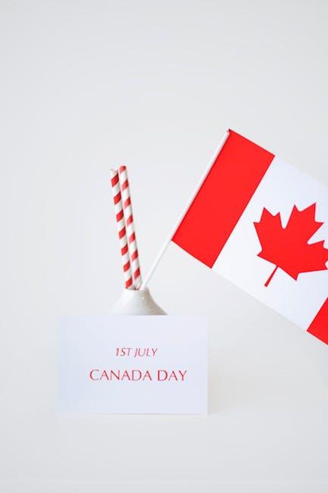 Reazioni_alla_vittoria_canadese_GH6iFLRuCP - Confidenze24 Source: Anna Nekrashevich - pexels - Minimalist Canada Day celebration with flag and festive straws on a white background.