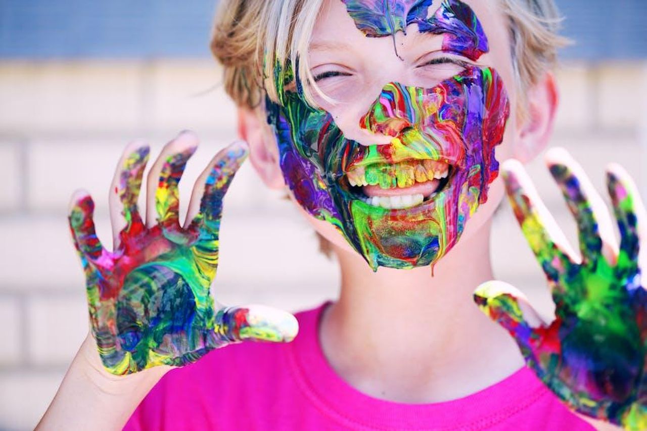Reazioni_divertenti_di_Kaavia_durante_la_vendita_4DPaAC3bY8 - Confidenze24 Source: Alexander Grey - pexels - A joyful child with vibrant face paint and hands, expressing happiness and creativity.