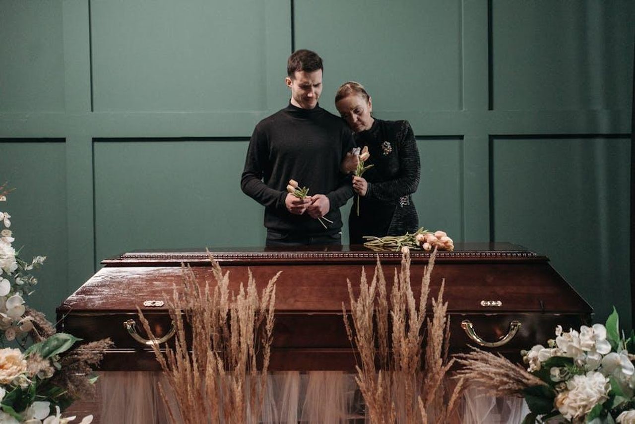 Reazioni_e_condoglianze_sDqGxSbUDg - Confidenze24 Source: Pavel Danilyuk - pexels - A touching image of a family mourning at a funeral, standing beside a coffin.