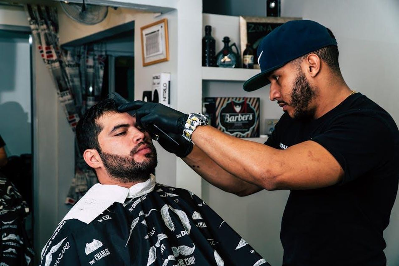 Recensioni_entusiastiche_degli_utenti_aTSzJheqEO - Confidenze24 Source: Jose Ricardo Barraza Morachis - pexels - Barber skillfully trims client's hair in modern barbershop setting.