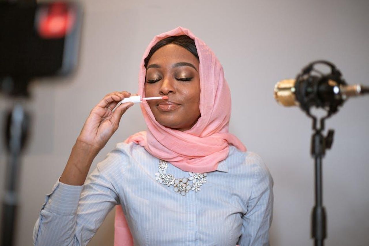 Recensioni_entusiastiche_sul_rossetto_OWYHpl3xUT - Confidenze24 Source: RDNE Stock project - pexels - A beautiful Black Muslim woman in hijab reviews lipstick in an indoor setting for her vlog.