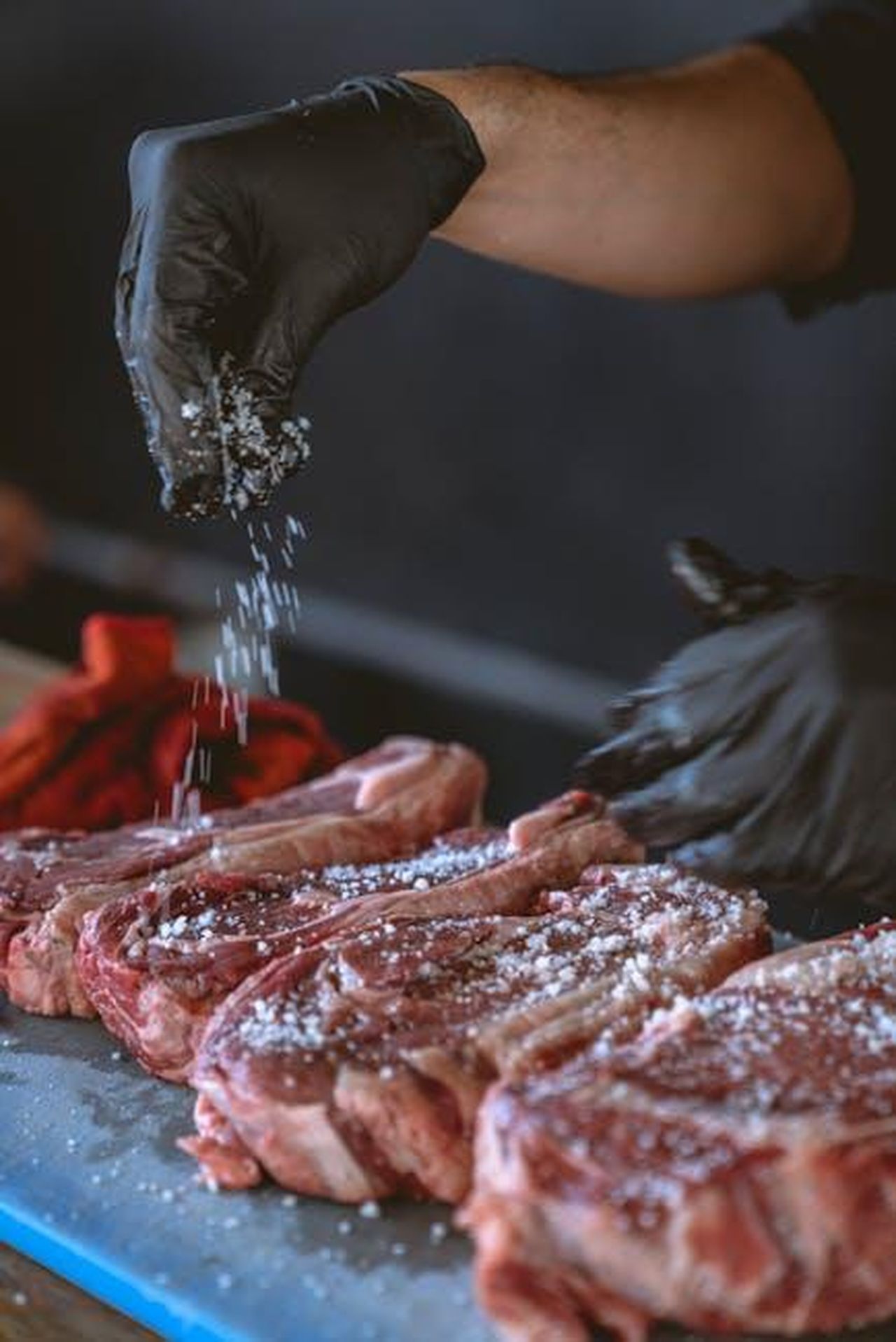 Ricetta_Filetto_di_manzo_con_patate_fingerling_rucola_e_crema_di_rafano_MYWn6hC0ZF - Confidenze24 Source: Los Muertos Crew - pexels - A chef seasons raw steaks with sea salt, perfecting the preparation process.