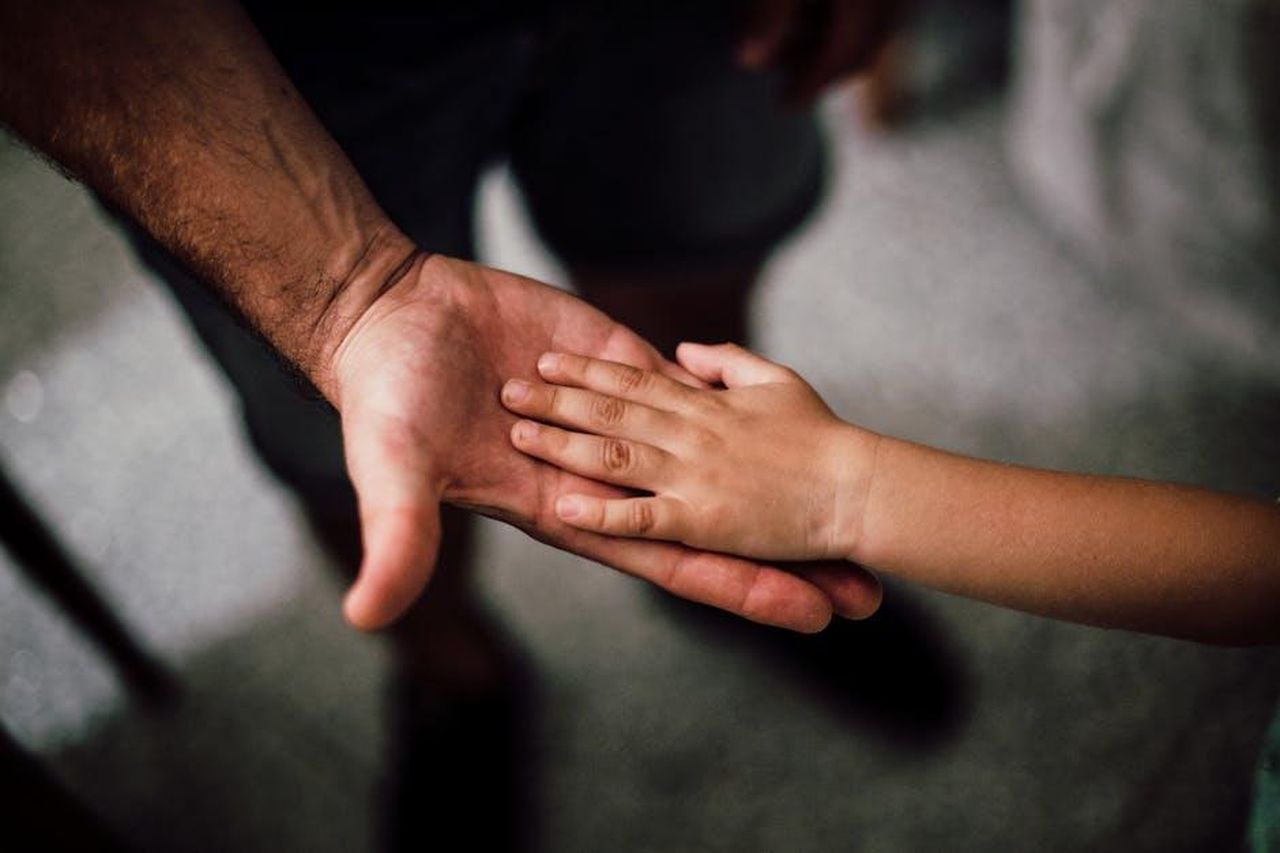Richiesta_di_supporto_per_il_figlio_e_spese_legali_cgySEGhCnb - Confidenze24 Source: Juan Pablo Serrano - pexels - Close-up of a child's hand resting gently on a man's hand, symbolizing love and support.