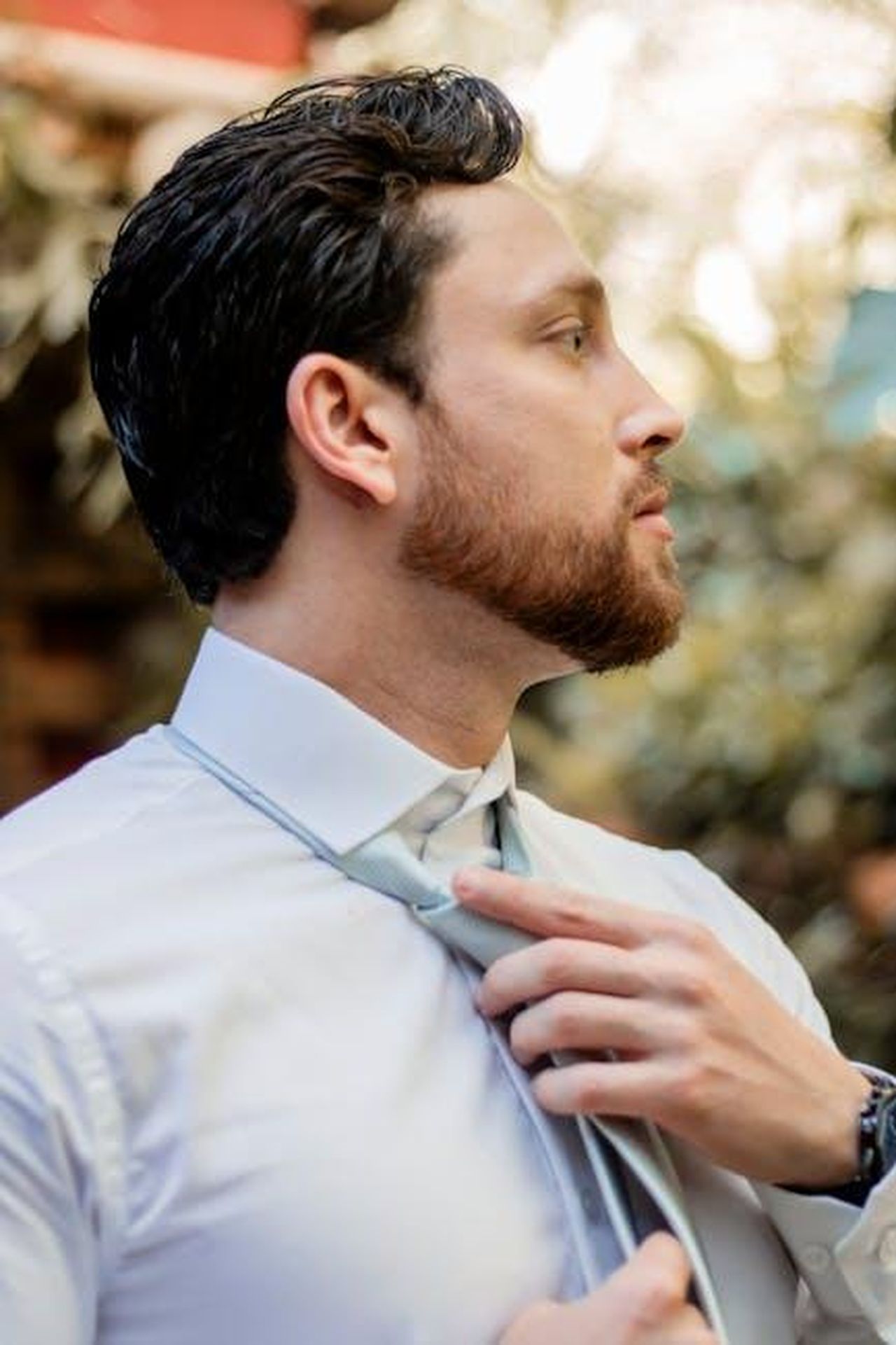 Riflessioni_sulla_sua_carriera_e_i_suoi_successi_ueg8UVBwdD - Confidenze24 Source: Vinicius Quaresma - pexels - Side profile of a businessman adjusting his tie, captured outdoors, exuding confidence.