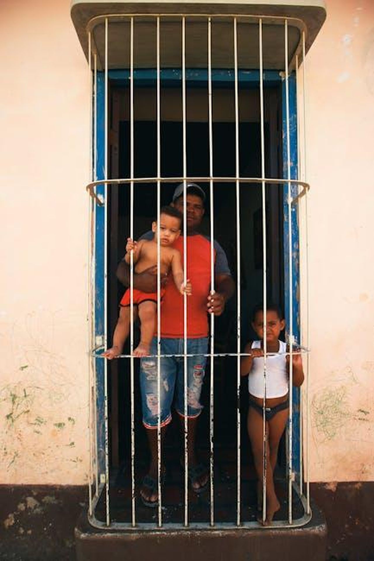 Riflessioni_sulle_dinamiche_sociali_Ufyn4M1LuU - Confidenze24 Source: Mehmet Turgut Kirkgoz - pexels - A family stands behind bars, sharing a joyful moment framed by security and togetherness.