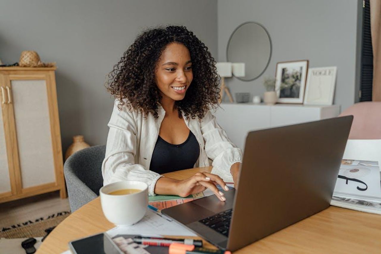 Rivedi_le_puntate_di_Beautiful_in_streaming_5eDNqxtWI3 - Confidenze24 Source: Antoni Shkraba - pexels - A woman sits at a round table, working on a laptop with a coffee cup nearby in a cozy home office setting.