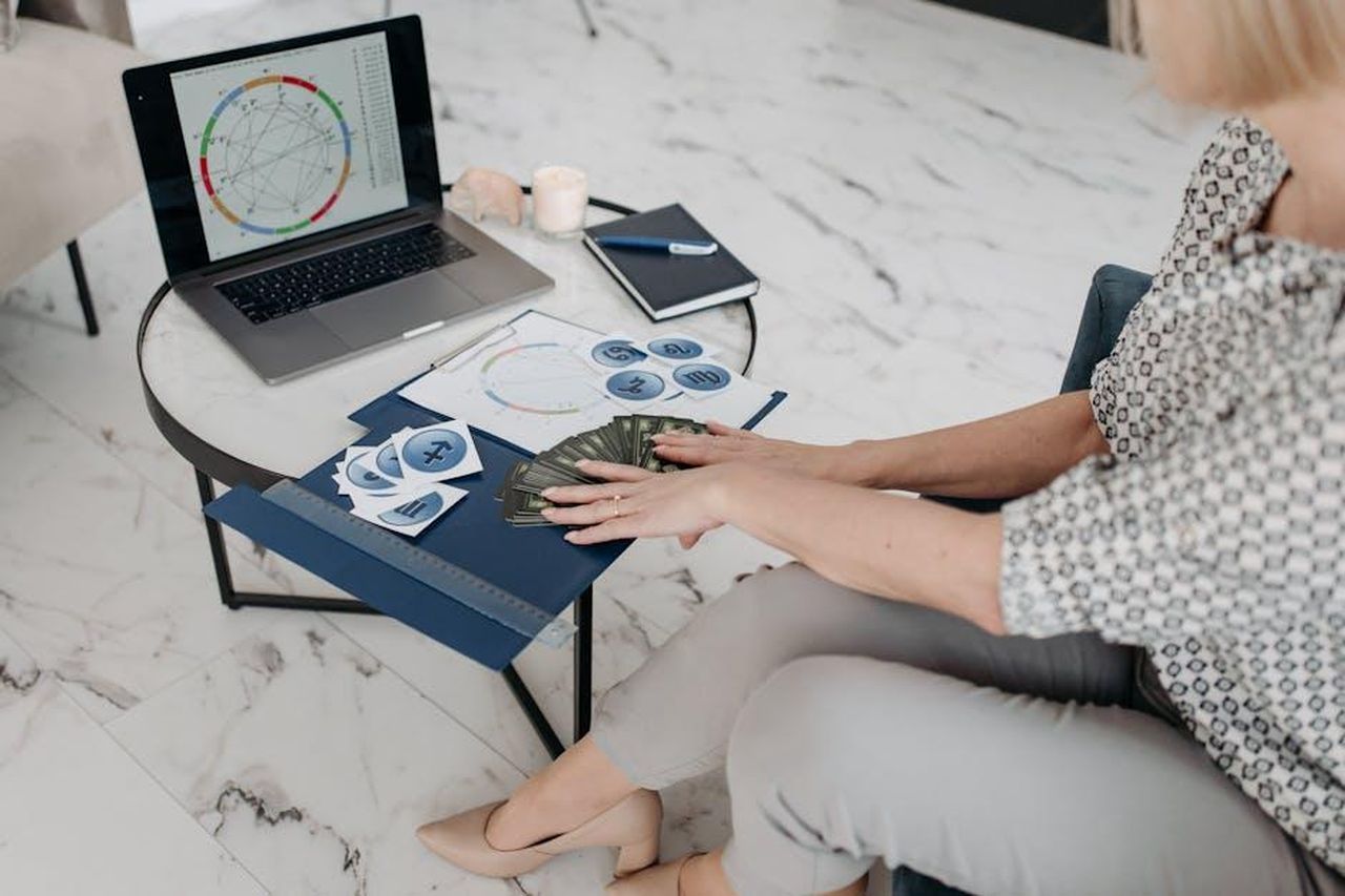Sagittario__URWZESSB1K - Confidenze24 Source: Pavel Danilyuk - pexels - Astrology scene with a woman using a laptop and tarot cards in a modern living room.