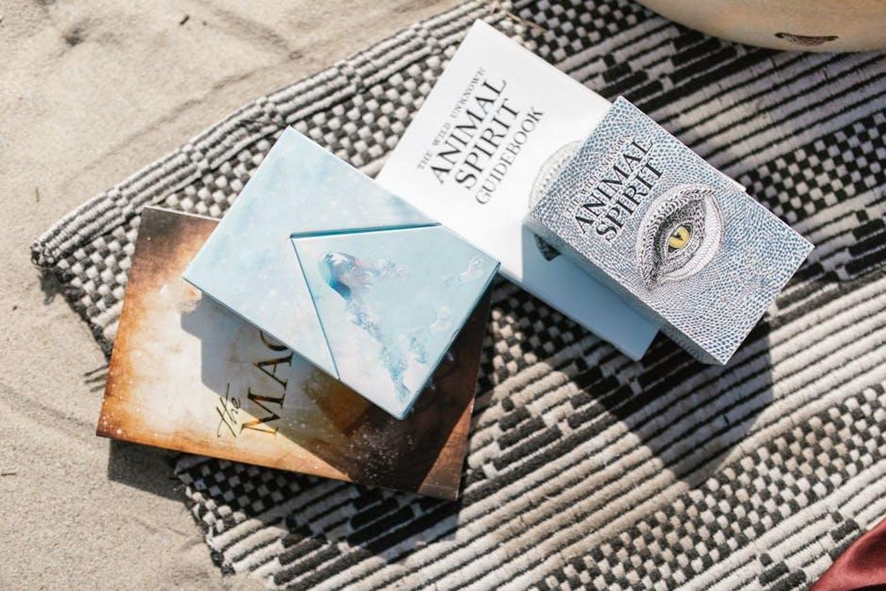 Sagittario_questioni_burocratiche_e_momenti_di_gioia_ZVTUMI6ZgE - Confidenze24 Source: RDNE Stock project - pexels - Animal spirit guidebooks placed on a patterned beach blanket in sunlight.