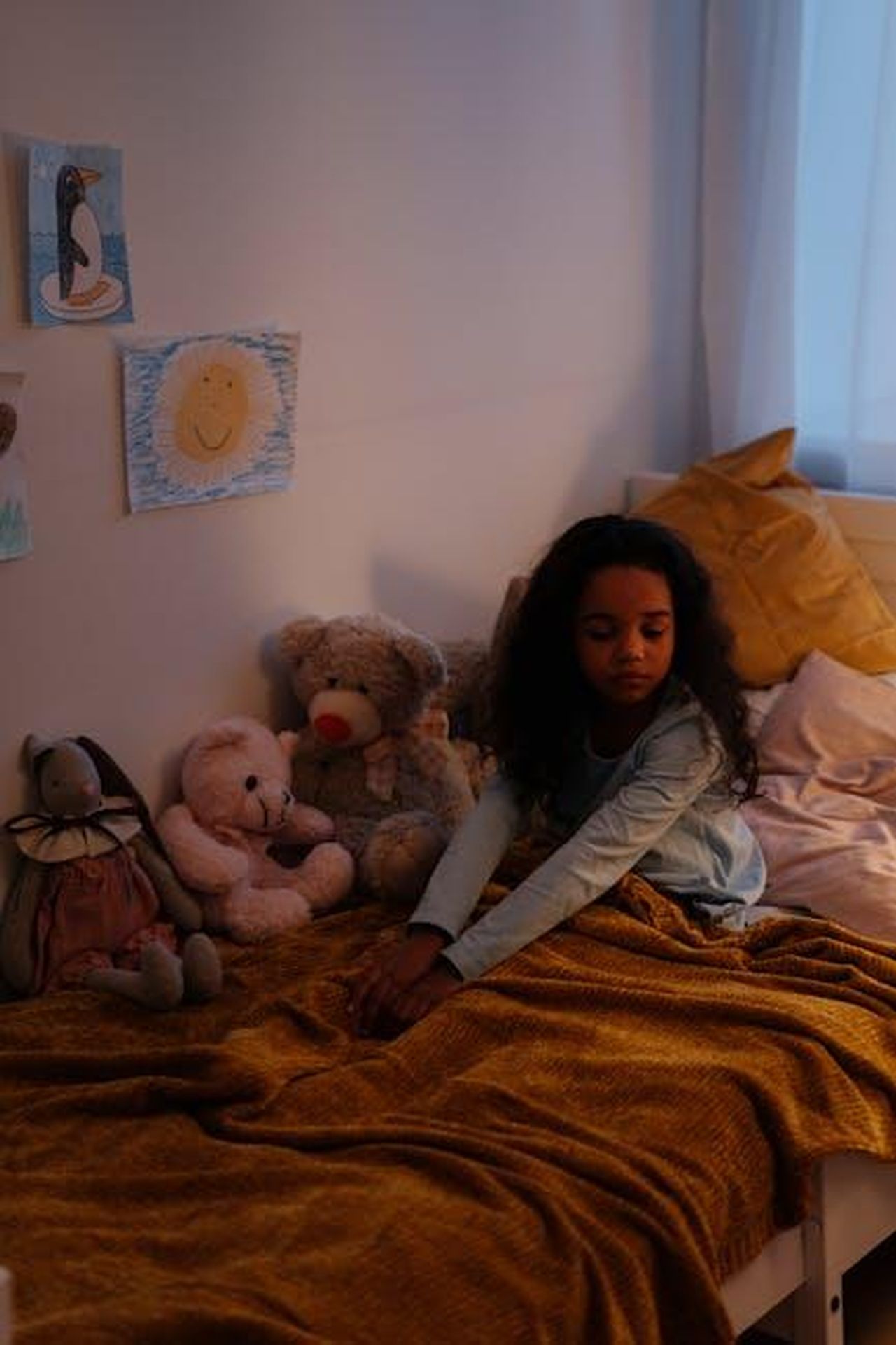 Saldi_imperdibili_su_American_Girl_Dolls_58FGWgwXFc - Confidenze24 Source: cottonbro studio - pexels - A young girl sits in a cozy bedroom surrounded by stuffed animals, creating a warm atmosphere.