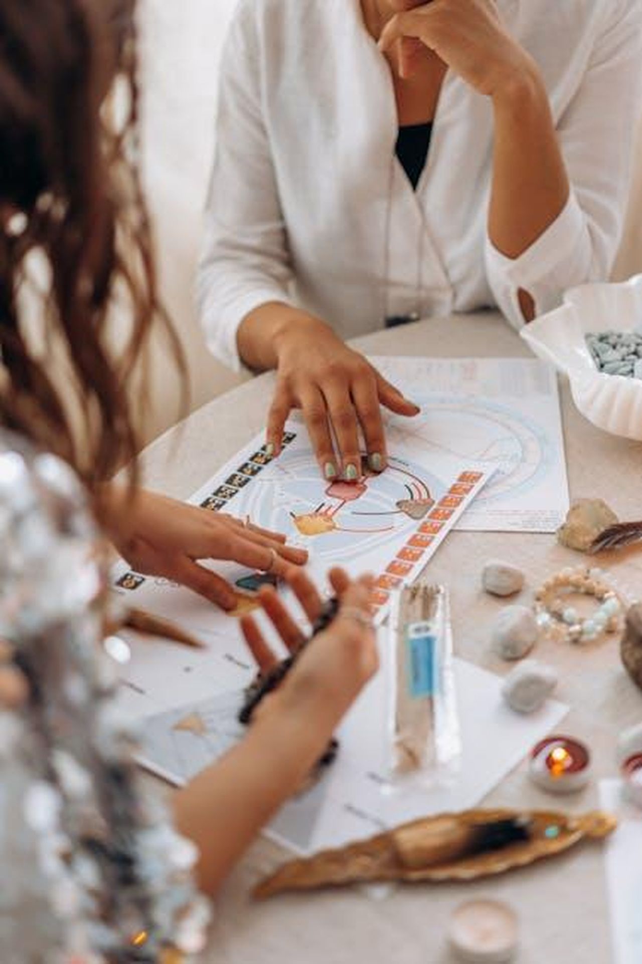 Segni_al_centro_della_graduatoria_VUIHDhRa2p - Confidenze24 Source: Mikhail Nilov - pexels - Two women exploring astrology and tarot readings at a table with stones and candles.
