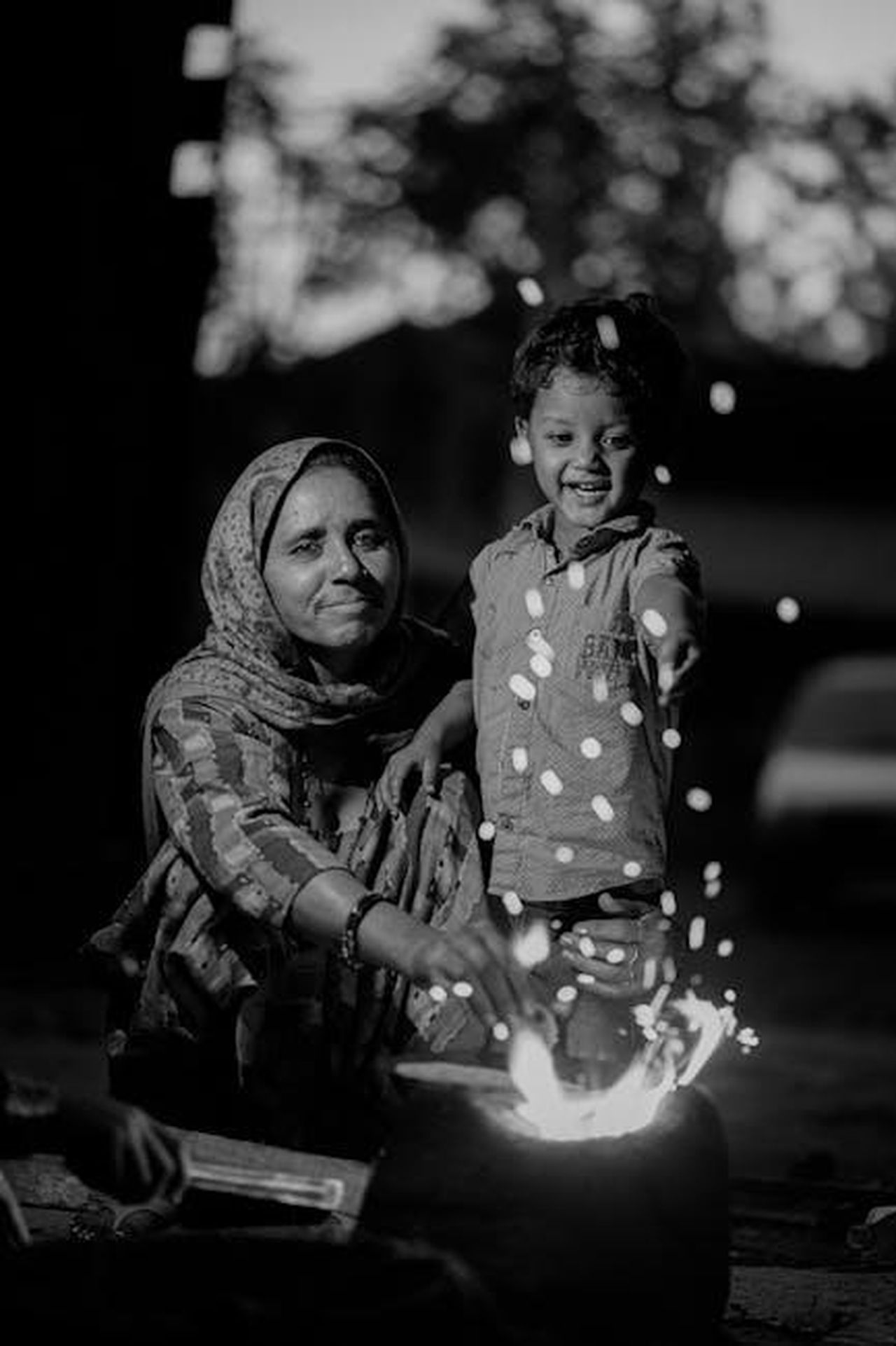 Simboli_di_Fuoco_Ariete_Leone_Sagittario_09PvRUcVah - Confidenze24 Source: Mir Burhan - pexels - A mother and young child smiling by a fire, enjoying a warm evening moment.