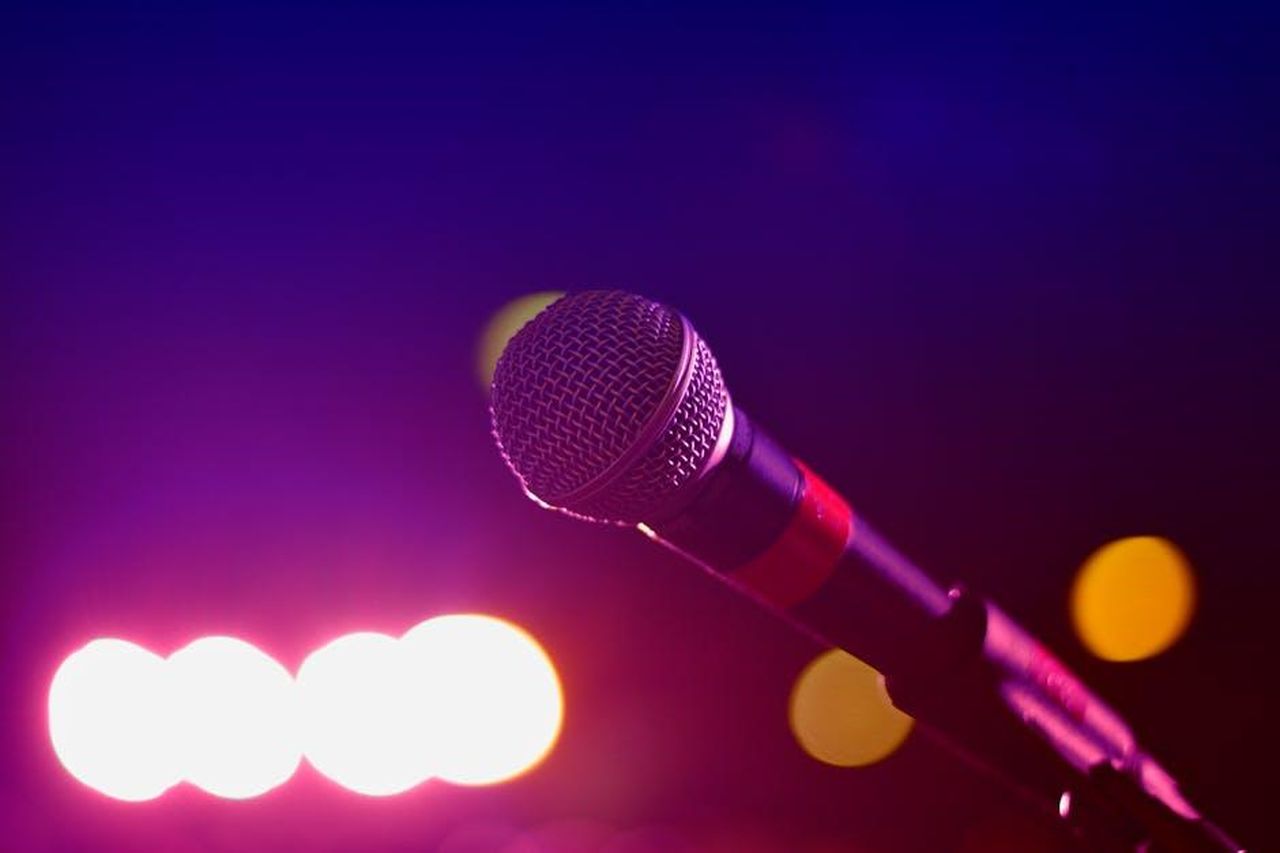 Stop_per_il_Grande_Fratello_cambio_programmazione_Mediaset_marzo_2025_yg9eQSnmf8 - Confidenze24 Source: Suvan Chowdhury - pexels - Colorful stage lighting highlights a microphone in a close-up view, perfect for music and performance themes.