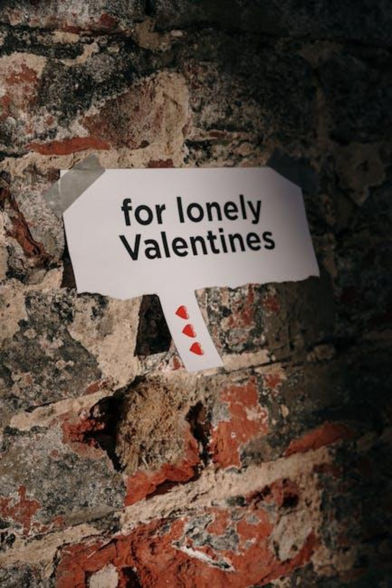 Tasha_Ghouri_e_Andrew_Le_Page_ySyOqmSviQ - Confidenze24 Source: cottonbro studio - pexels - A paper note reading 'for lonely Valentines' taped to a rustic brick wall, creating a moody atmosphere.