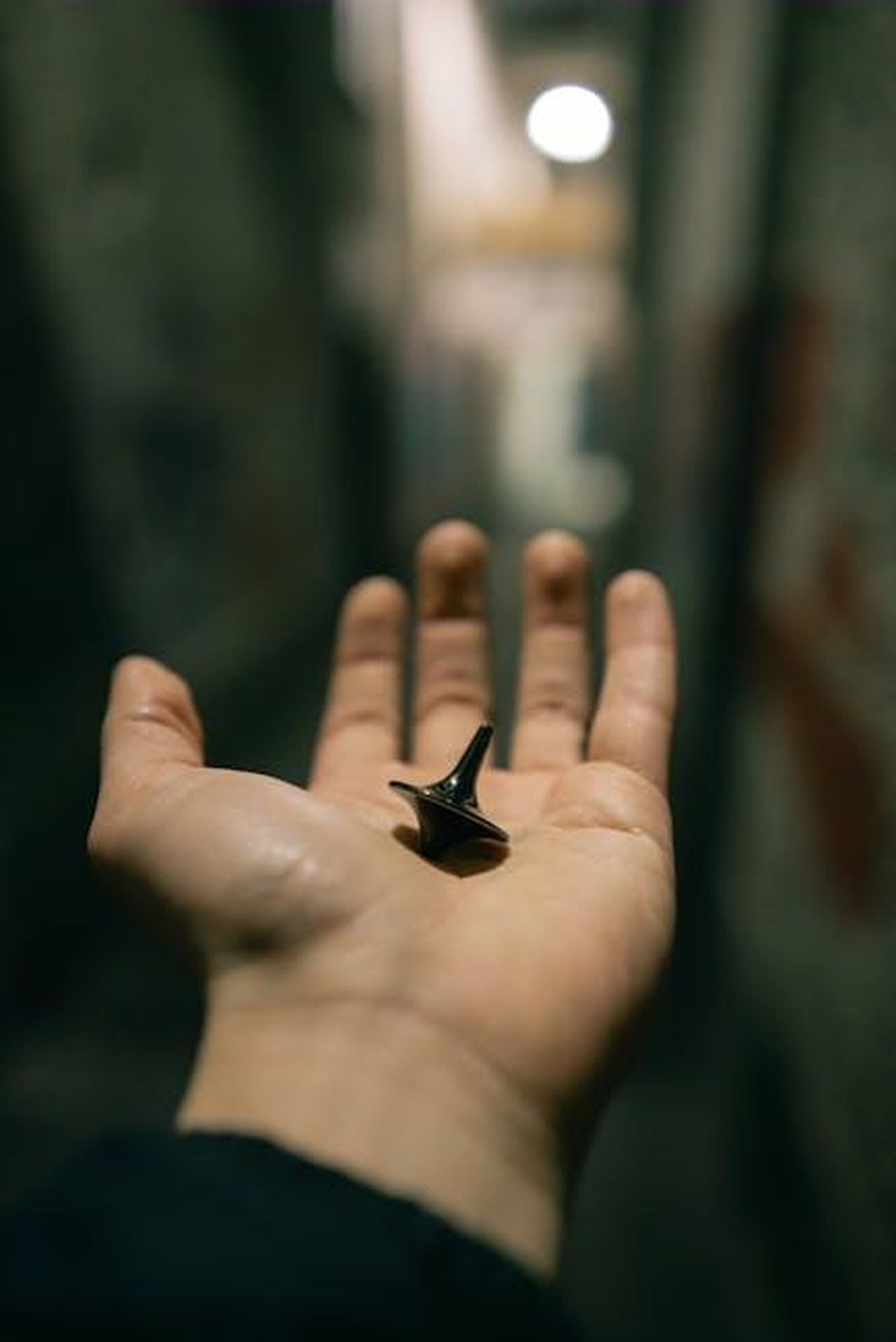 Tensioni_tra_Zeudi_e_Helena_gyKiXeMwQ3 - Confidenze24 Source: Ahmet Yüksek ✪ - pexels - A hand holds a spinning top in an atmospheric alley, evoking mystery and intrigue.