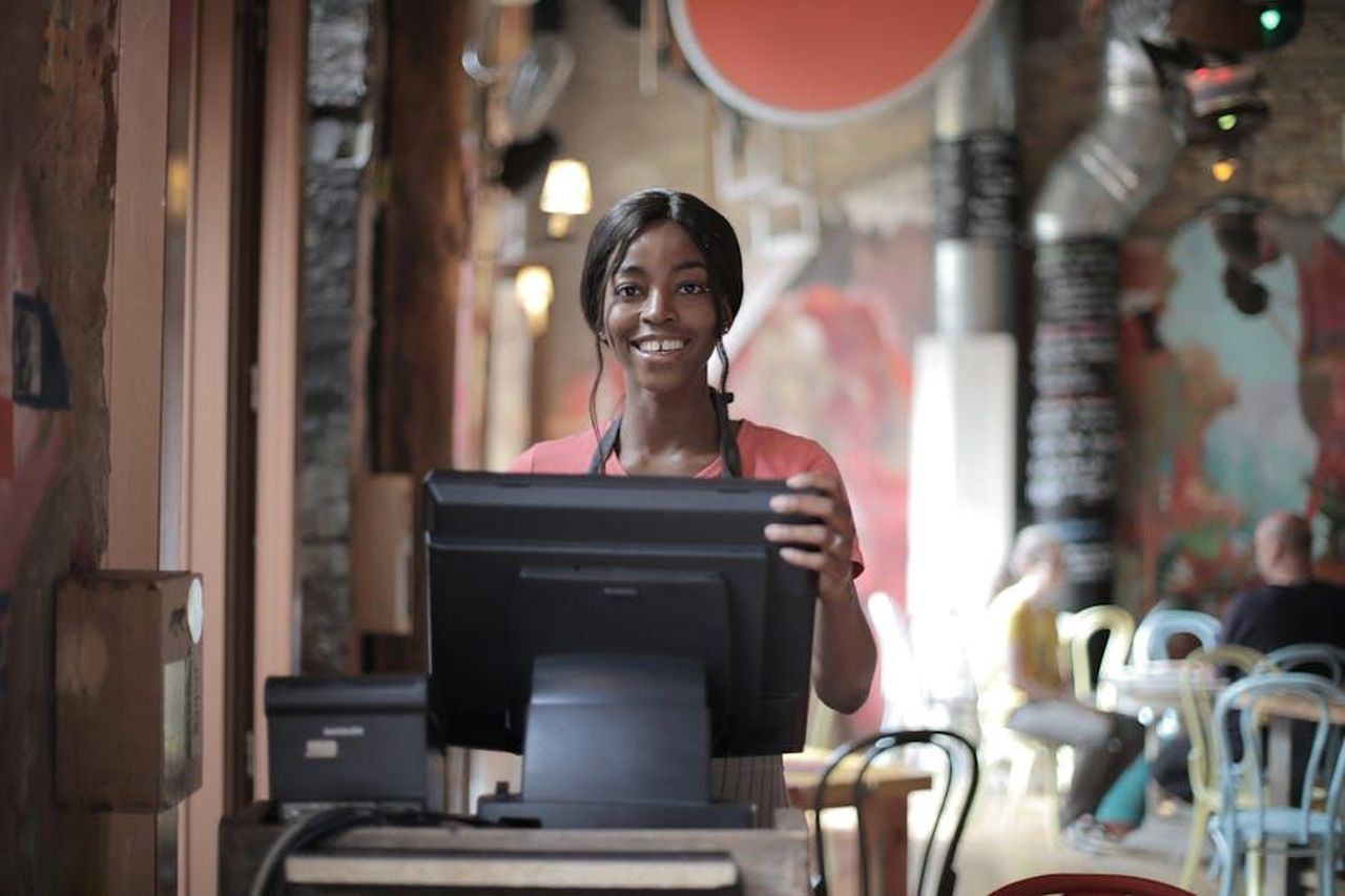 Testimonianze_di_utenti_soddisfatti_fIyNd3wR5N - Confidenze24 Source: Andrea Piacquadio - pexels - Positive young woman in uniform smiling while standing at counter desk in cafe