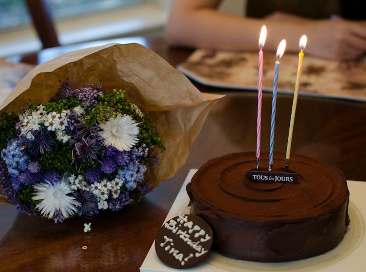 Tina_Cipollari_continua_le_sue_conoscenze_in_particolare_con_Cosimo_6xnVkRSkyv - Confidenze24 Source: Trac Vu - pexels - Celebrate with chocolate cake and floral bouquet, featuring lighted candles for a festive occasion.