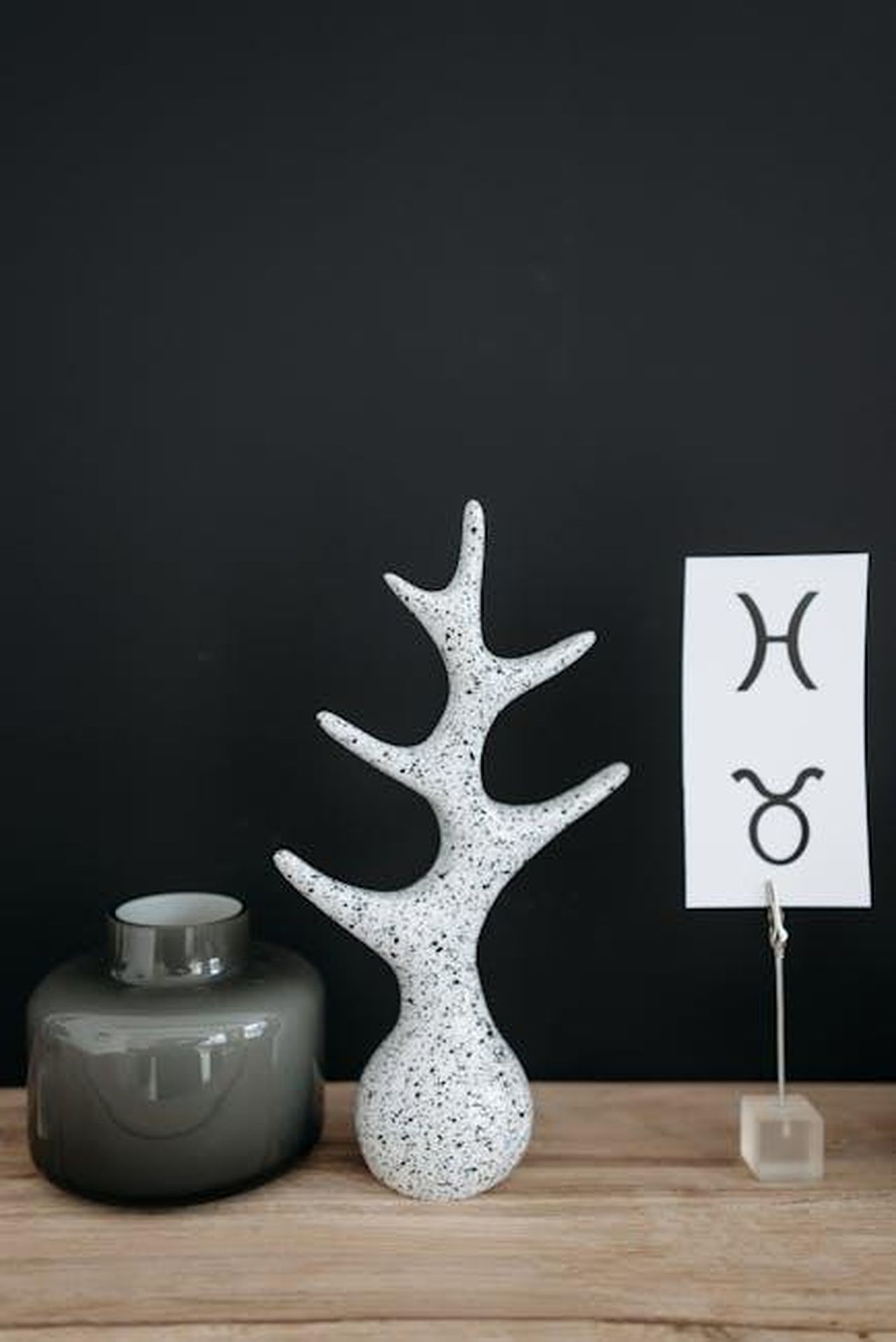 Toro__Riflessione_e_pianificazione_CQOaiv8wTI - Confidenze24 Source: Pavel Danilyuk - pexels - Elegant minimalist display with ceramic sculpture and zodiac signs on a wooden shelf, perfect for modern decor.