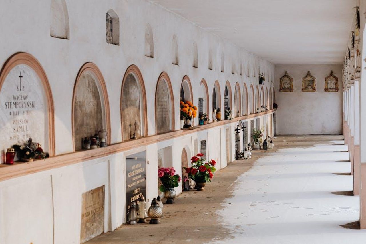 Tributi_e_reazioni_CO89qgsnwg - Confidenze24 Source: Photo By: Kaboompics.com - pexels - Quiet corridor in a cemetery with rows of tombs decorated with flowers and candles.