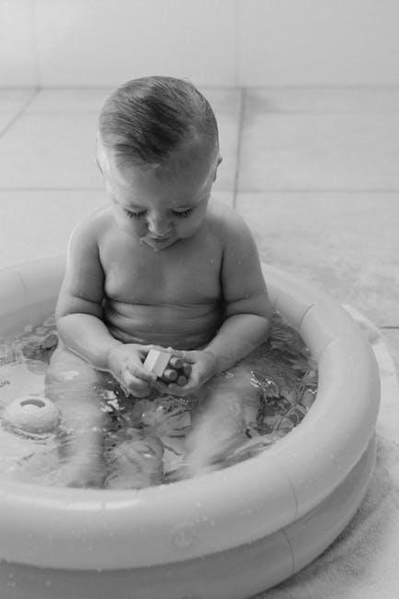 Un_Momento_Imbarazzante_nella_Sua_Carriera_6tdPYAxKs6 - Confidenze24 Source: juliane Monari - pexels - Black and white photo of a baby playing with toys in an indoor inflatable pool.