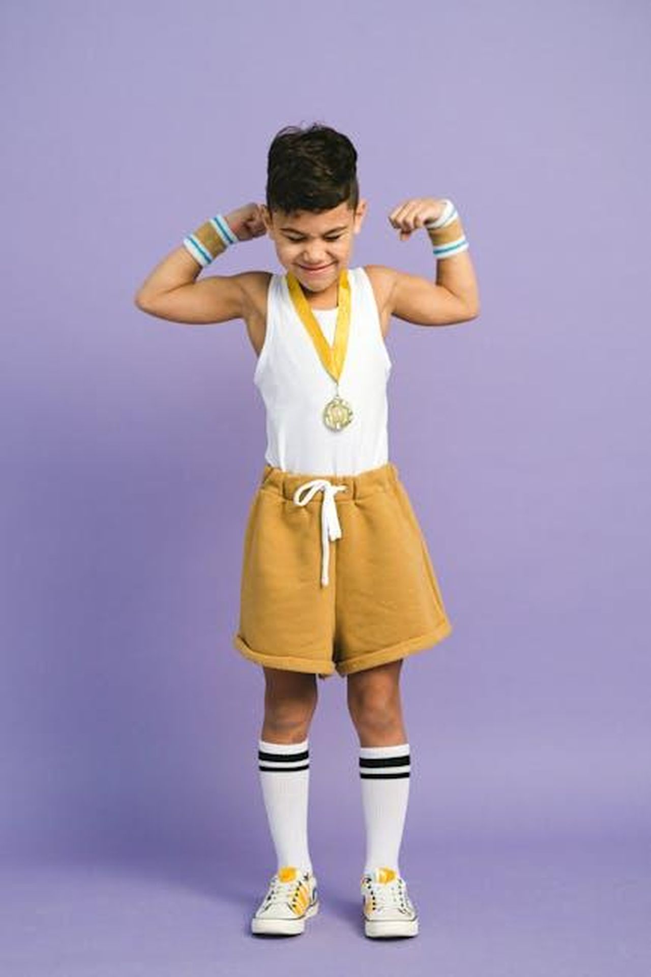 Un_attore_pluripremiato_Yh0z1QqQP6 - Confidenze24 Source: Anna Shvets - pexels - Joyful boy flexing with a medal, symbolizing victory and achievement.