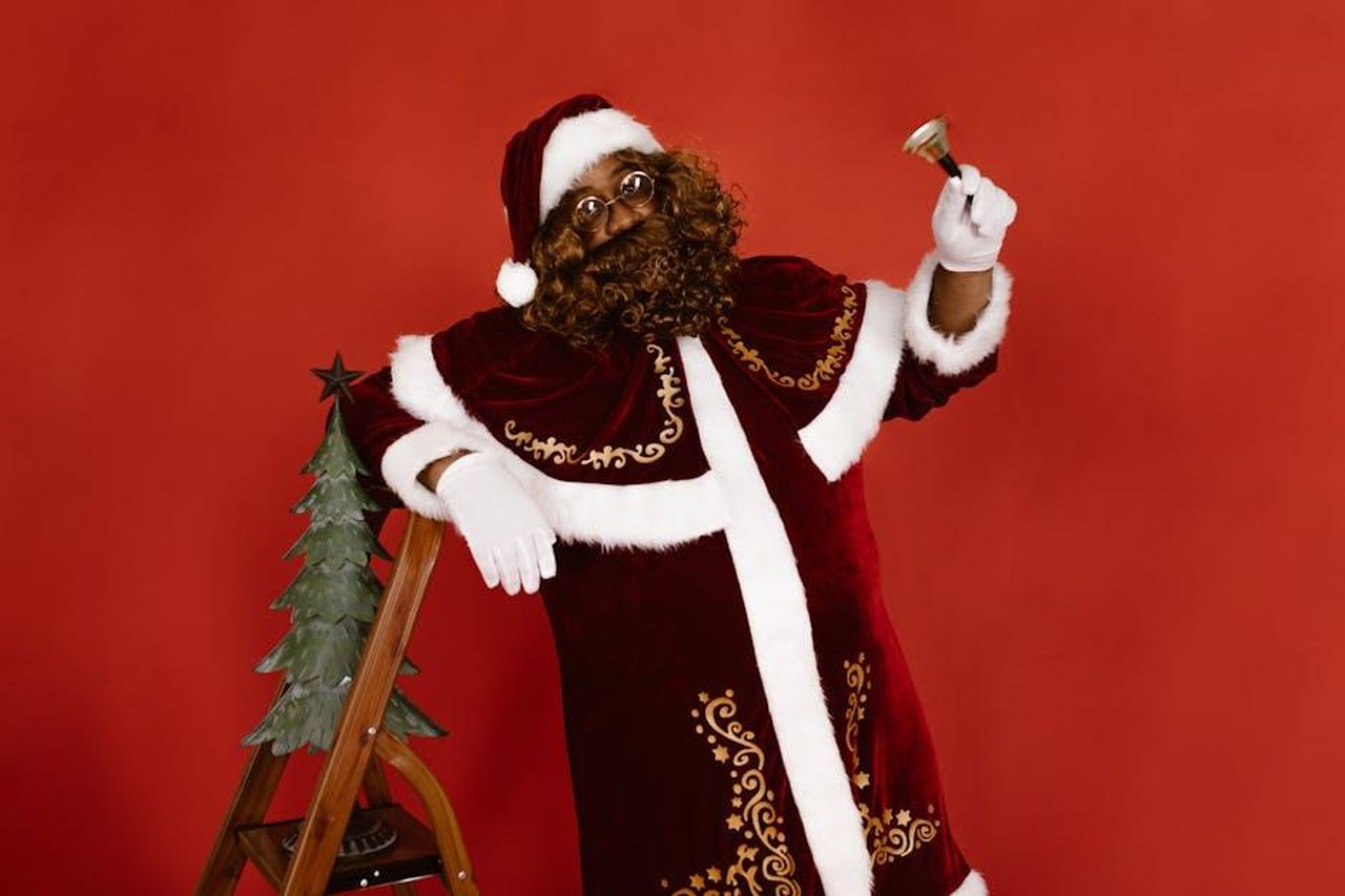 Un_equilibrio_tra_tradizione_e_inclusivit_NDgE09And6 - Confidenze24 Source: RDNE Stock project - pexels - Black Santa Claus in a festive pose ringing a bell, symbolizing holiday cheer and inclusivity.