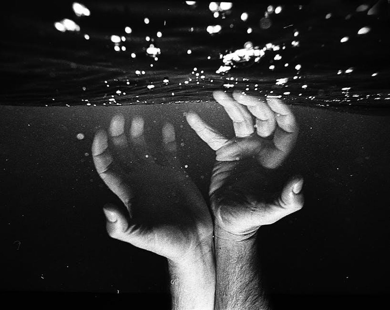Un_finto_flirt_che_ha_acceso_i_sospetti_ERqsF11gYi - Confidenze24 Source: Mariana Montrazi - pexels - Black and white photo of hands reaching above the water with dramatic lighting.