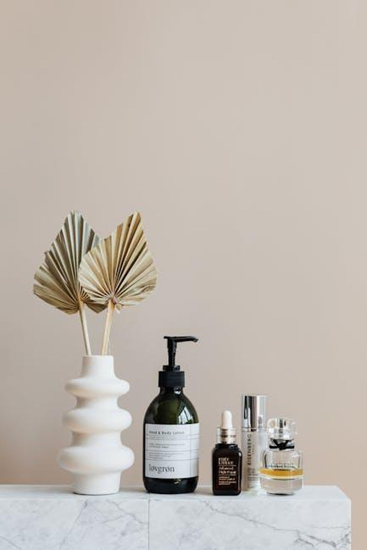 Un_prodotto_di_alta_qualit_a_un_prezzo_accessibile_bOfjTv3Odc - Confidenze24 Source: Photo By: Kaboompics.com - pexels - Minimalist bathroom shelf featuring skincare bottles and decorative beige vase.