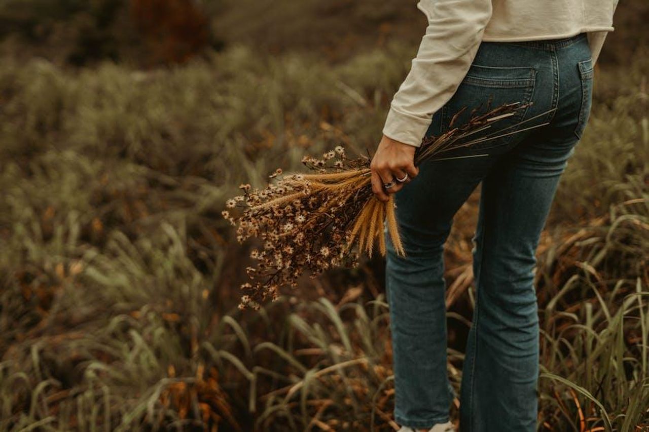 Un_riepilogo_degli_episodi_precedenti_Gallo_ha_obbligato_Damiano_a_rimanere_in_ufficio_yPuJdAftcE - Confidenze24 Source: Gihan Bandara - pexels - A woman standing in a grassy field holding a bouquet of wildflowers, capturing a rustic lifestyle.