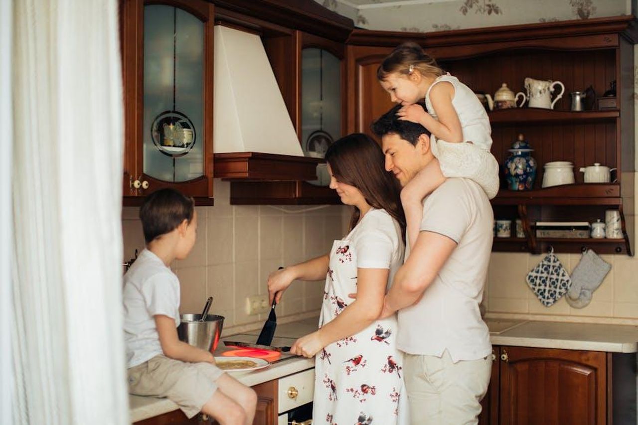 Unico_stile_di_vita_nocIicPM0s - Confidenze24 Source: Elina Fairytale - pexels - A joyful family cooking together in their cozy home kitchen, showcasing love and togetherness.