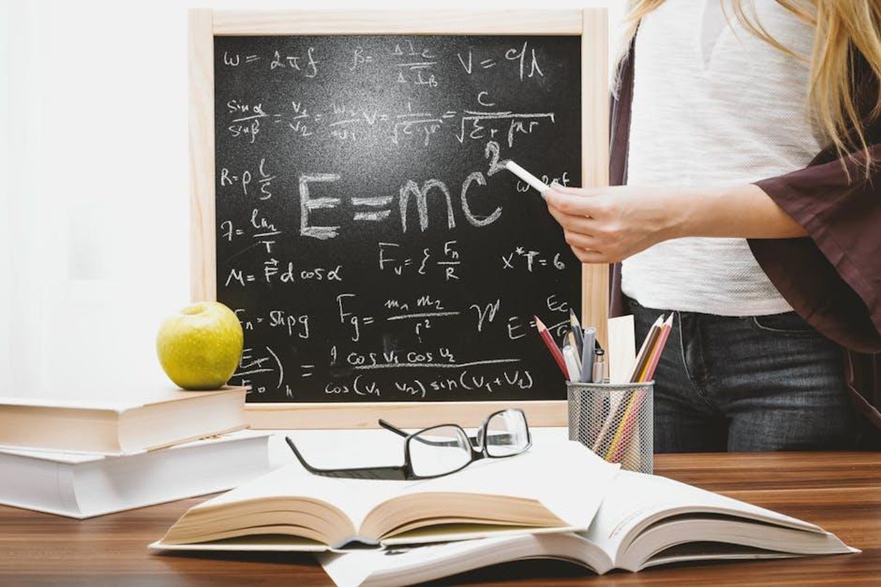 Uomini_e_donne_leader_degli_ascolti_del_pomeriggio_9pvb79azJM - Confidenze24 Source: JESHOOTS.com - pexels - Woman writing physics equations on a blackboard with books and an apple on the desk.