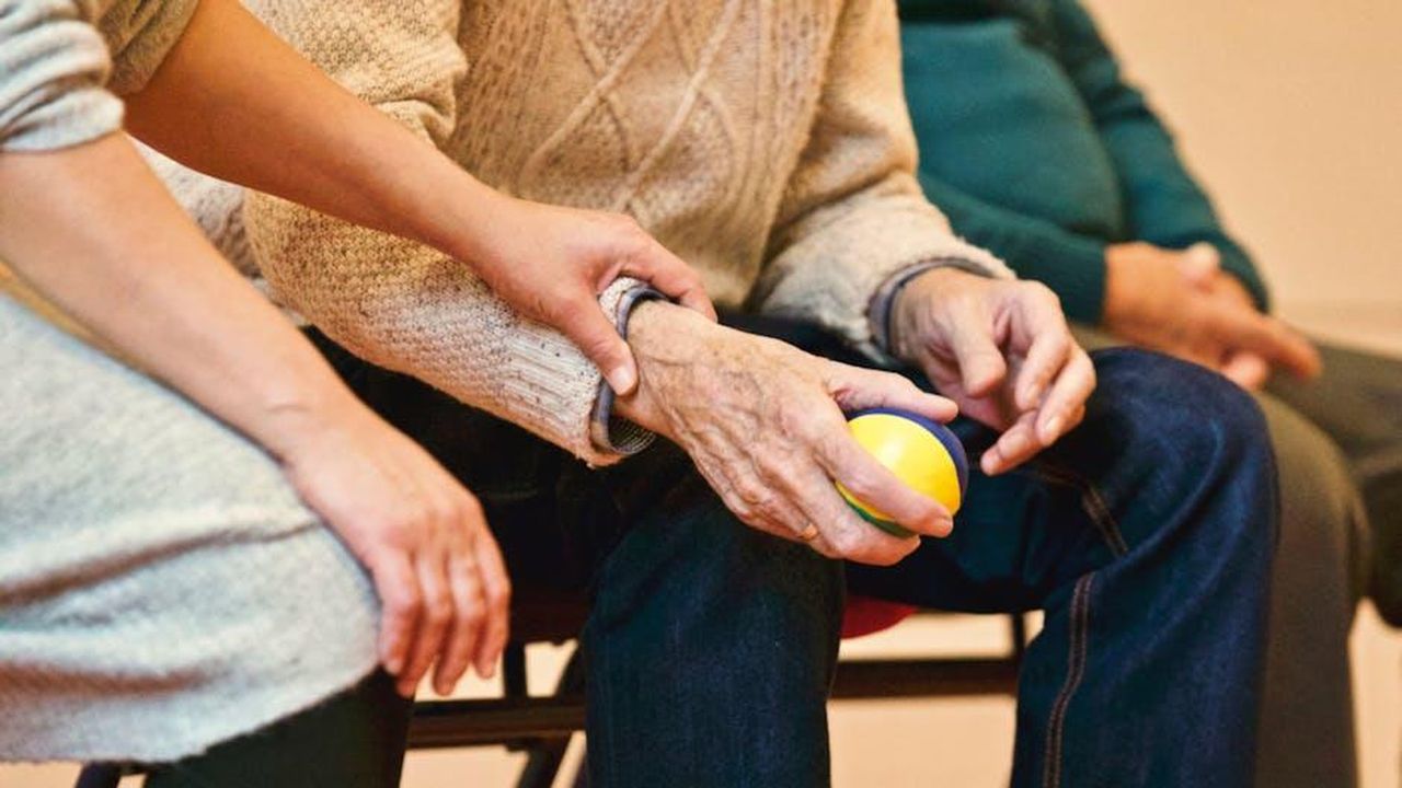 Upas_tratta_il_tema_dellAlzheimer_la_fase_avanzata_w1ZGV3gieJ - Confidenze24 Source: Matthias Zomer - pexels - An elderly person receives support from a caregiver, holding hands indoors, showcasing compassion.