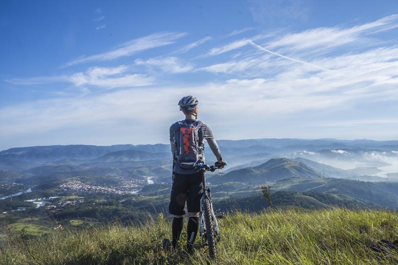 Van_Aert_Ci_hanno_indirizzato_dalla_parte_sbagliata_vDxx5ERu2H - Confidenze24 Source: Pixabay - pexels - A cyclist stands on a hill, gazing at a stunning mountain landscape on a bright sunny day.