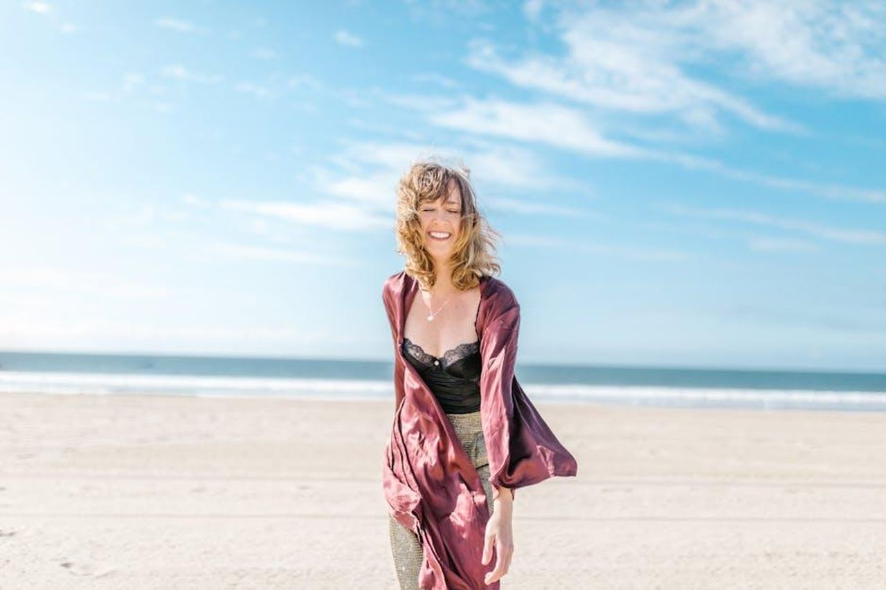 Vergine_23_agosto__22_settembre_k0Ffa9QjLh - Confidenze24 Source: RDNE Stock project - pexels - Woman in elegant attire smiling widely on a sunny beach, embodying freedom and joy.