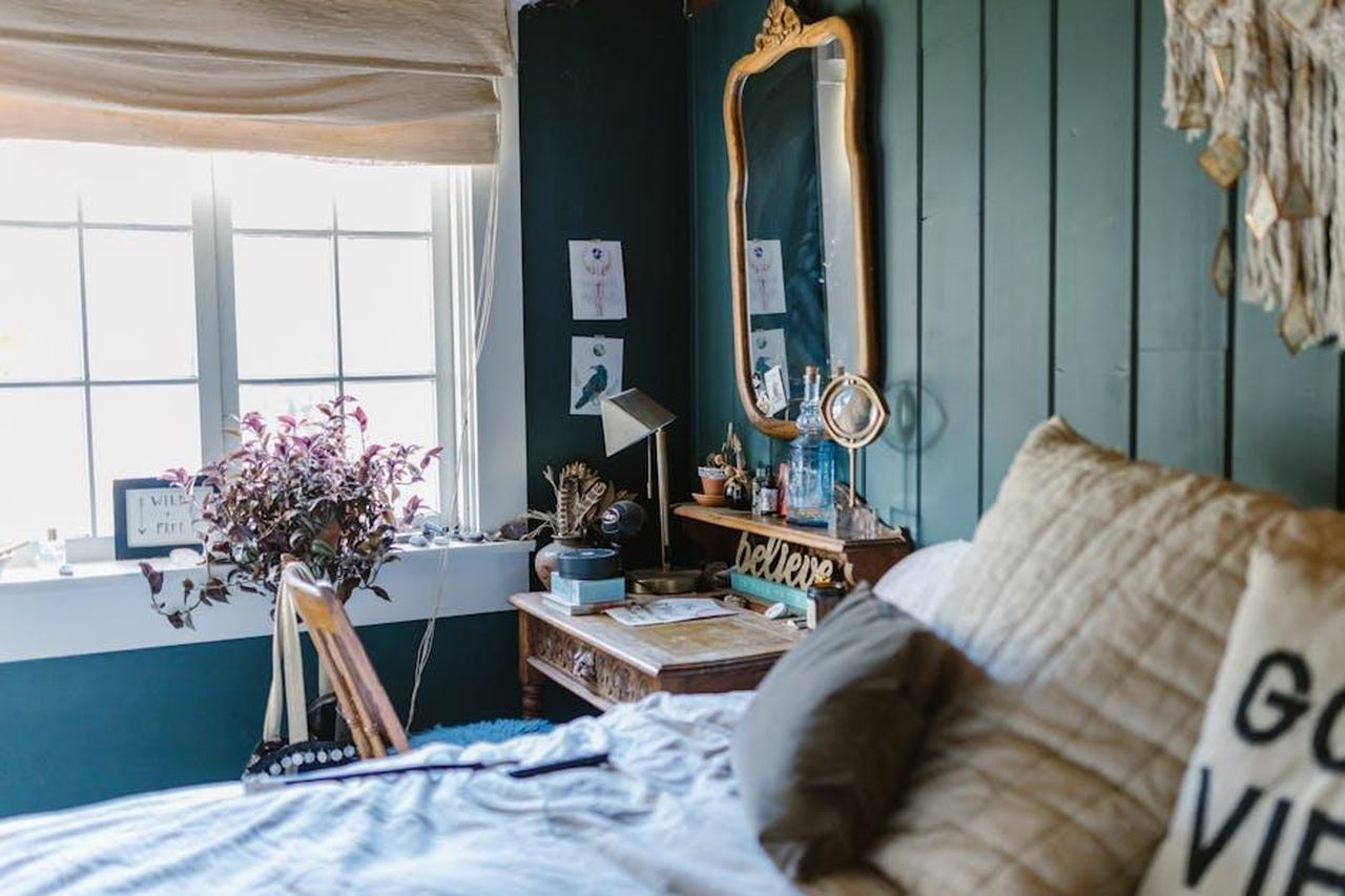 Vergine_sfide_professionali_GJjKOYXfjv - Confidenze24 Source: RDNE Stock project - pexels - A cozy bedroom with green walls featuring crystals and a vintage mirror.