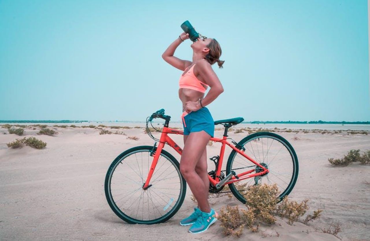 Voglio_aiutare_i_giovani_a_crescere_XdYLwpi11E - Confidenze24 Source: The Lazy Artist Gallery - pexels - Athletic woman drinking water while biking in the Dubai desert landscape.