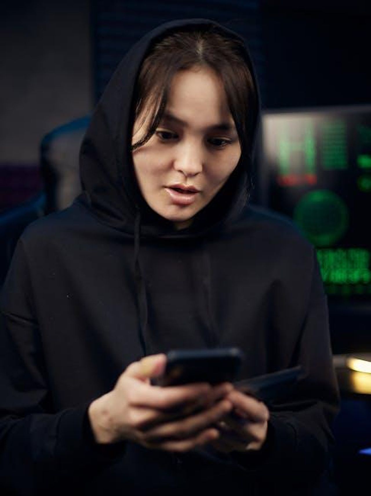 Yeim_e_Ilknur_inscenano_un_furto_per_soldi_ma_Gzide_scopre_tutto_e_le_affronta_faccia_a_faccia_7Zt6MGQ4Vi - Confidenze24 Source: Mikhail Nilov - pexels - A young woman in a black hoodie uses her smartphone indoors, surrounded by tech gear.