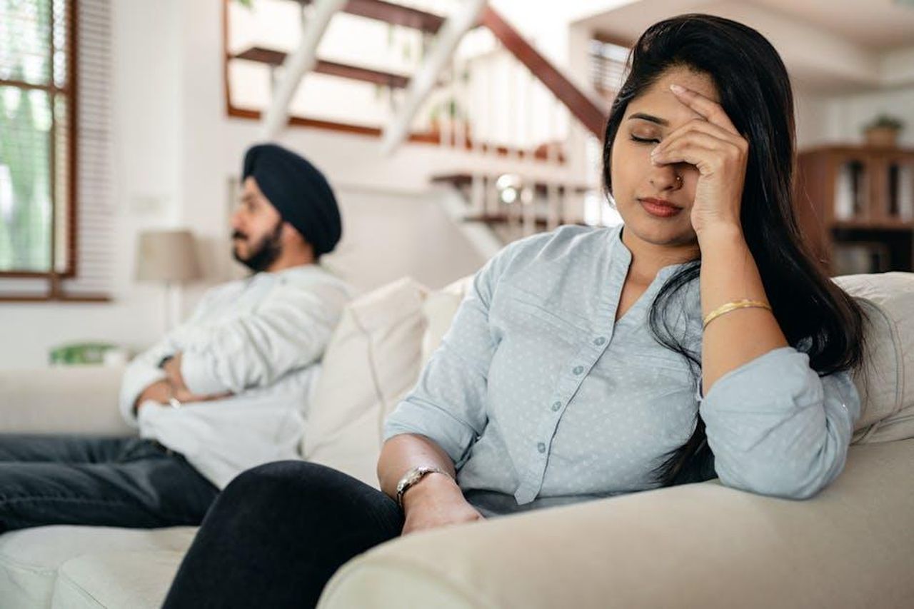 Yeim_minaccia_Dilek_e_la_aggredisce_per_farle_perdere_il_bambino_Gq5uc6a4TE - Confidenze24 Source: Ketut Subiyanto - pexels - A young couple sitting on a couch indoors, showing signs of stress and frustration.