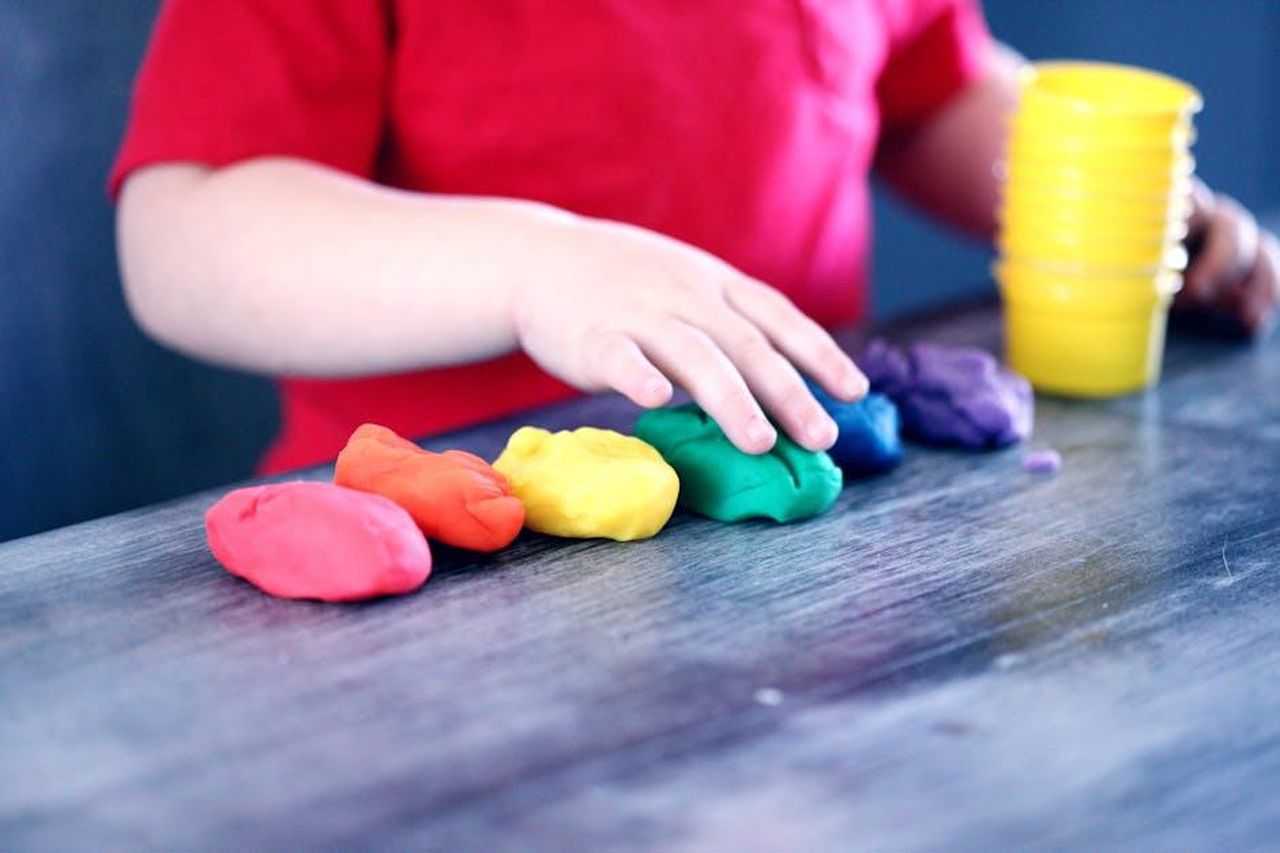 Yesim_affida_la_sua_bambina_a_una_tata_inesperta_iZFyhrEtW3 - Confidenze24 Source: Alexander Grey - pexels - A young child with rainbow-colored modeling clay and stacking cups on a table indoors.