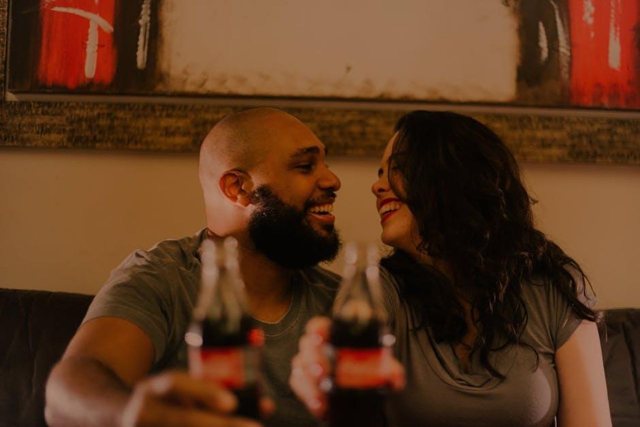 Yesim_pronta_a_far_fuori_Tarik_prepara_per_lui_una_serata_romantica_MHM0rnsVgT - Confidenze24 Source: Edward Eyer - pexels - A joyful couple shares a soda and laughter indoors, capturing the essence of love and togetherness.