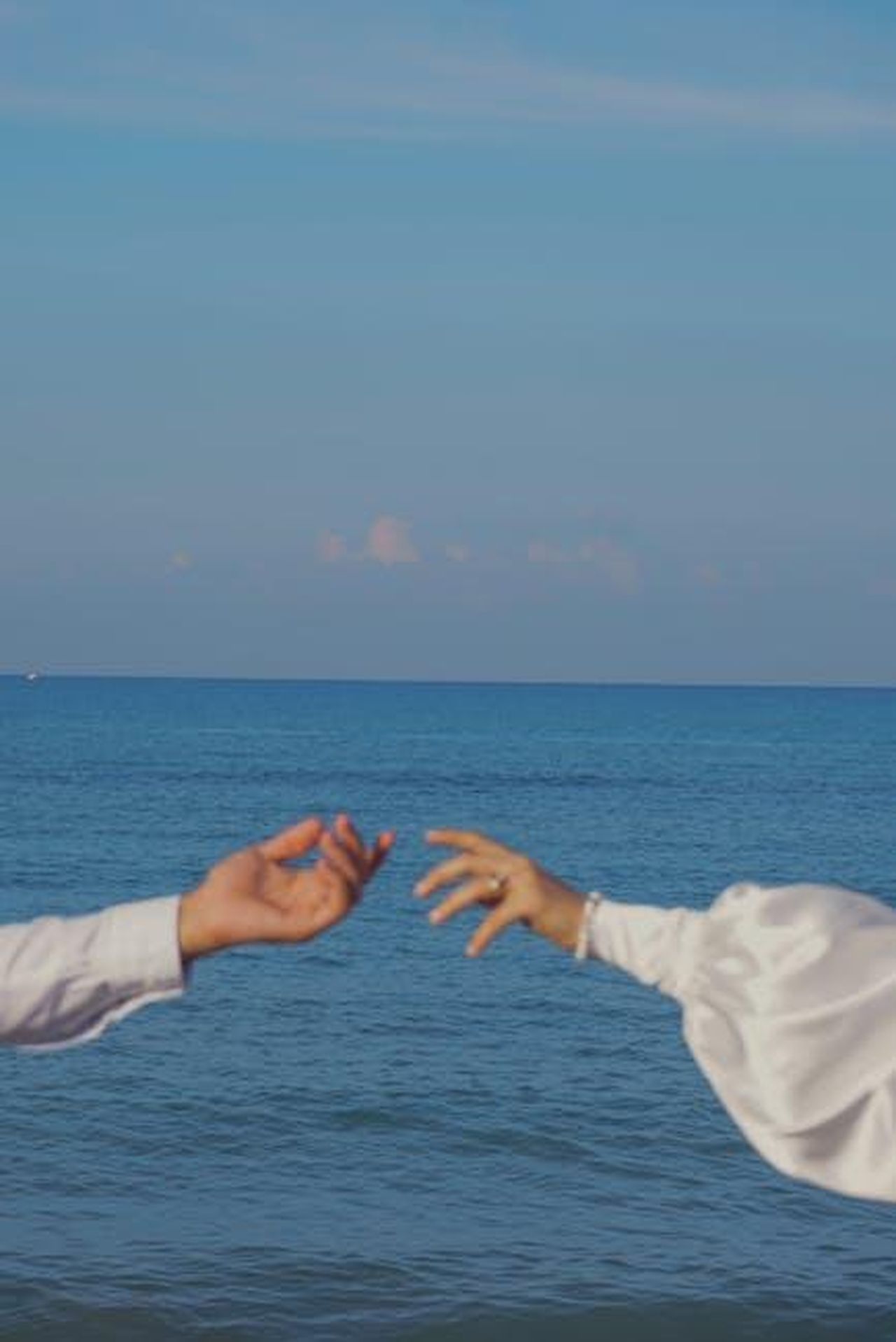 11_settembre_2023_Shayk_torna_da_Brady_EGuvvVuGIO - Confidenze24 Source: Burcufilms - pexels - Two hands reaching towards each other over the serene Turkish seaside.