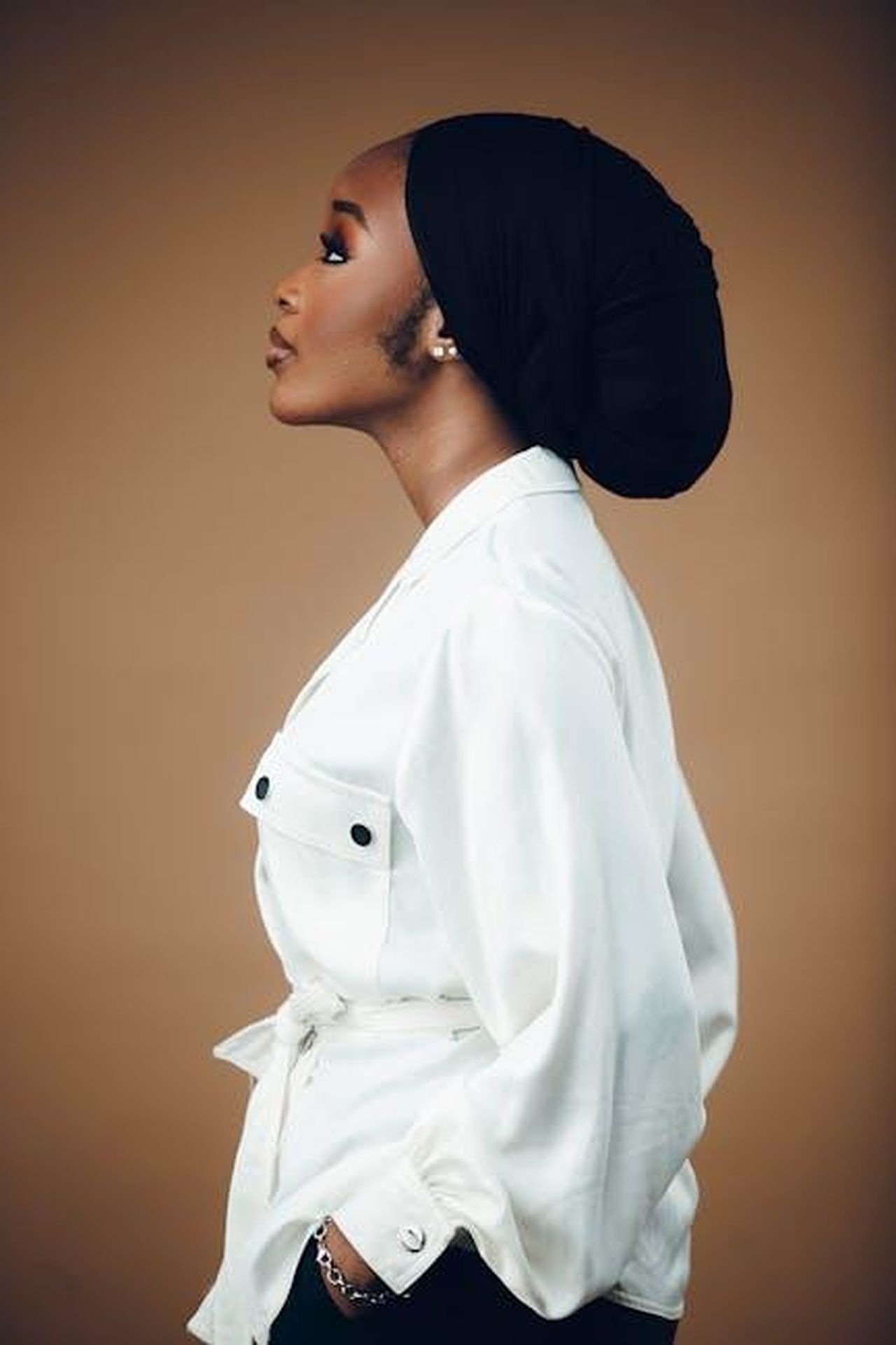 1_Commenti_di_Danny_su_Im_A_Celebrity_s4laZCxr78 - Confidenze24 Source: Darkshade Photos - pexels - Elegant side profile portrait of a woman in a stylish white coat with a neutral background.