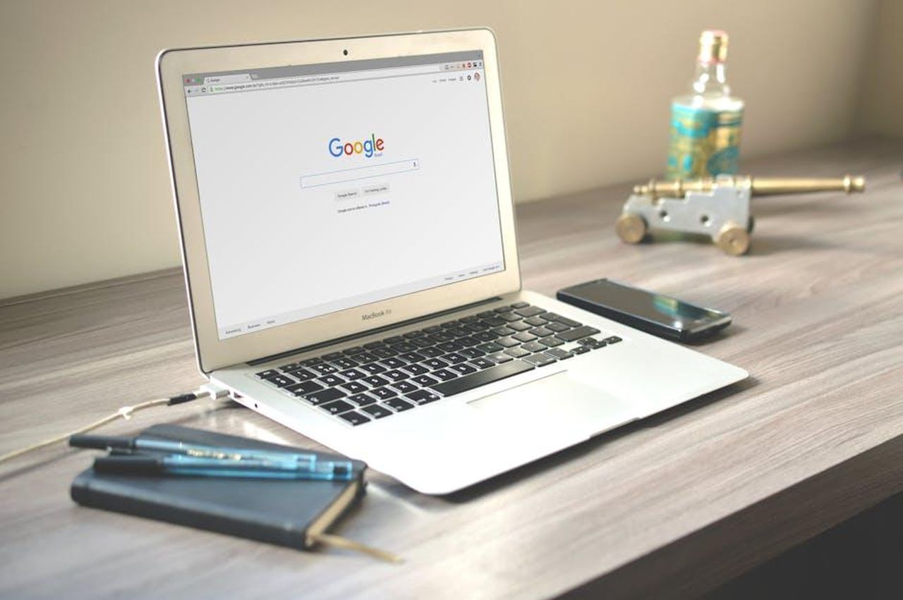 3_Amy_e_Lily_non_sono_state_perquisite_gGsZQUPqaO - Confidenze24 Source: Caio - pexels - A neat workspace featuring a laptop displaying Google search, a smartphone, and a notebook on a wooden desk.