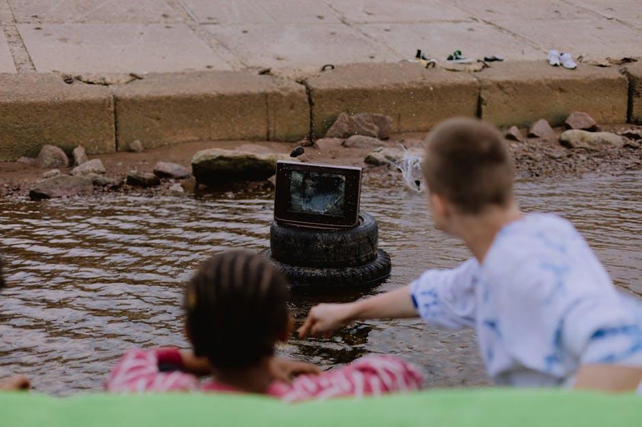 5_Ritorno_sui_social_media_OzO9gRjWgl - Confidenze24 Source: cottonbro studio - pexels - Teenagers watching a broken TV in water, creating a unique scene of urban exploration.