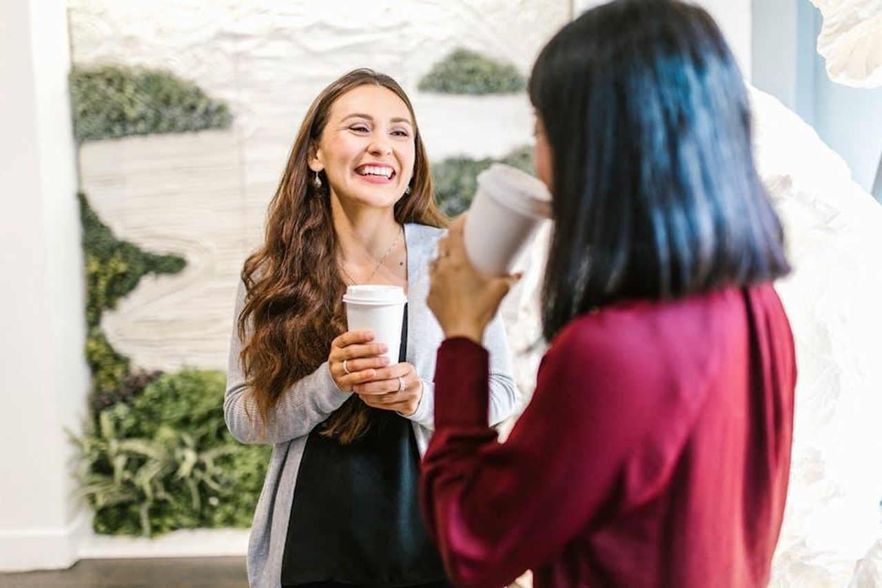 Adele_parla_per_John_rOq9PICEa0 - Confidenze24 Source: RDNE Stock project - pexels - Two women in a modern office setting enjoying a casual coffee break, highlighting teamwork and relaxation.