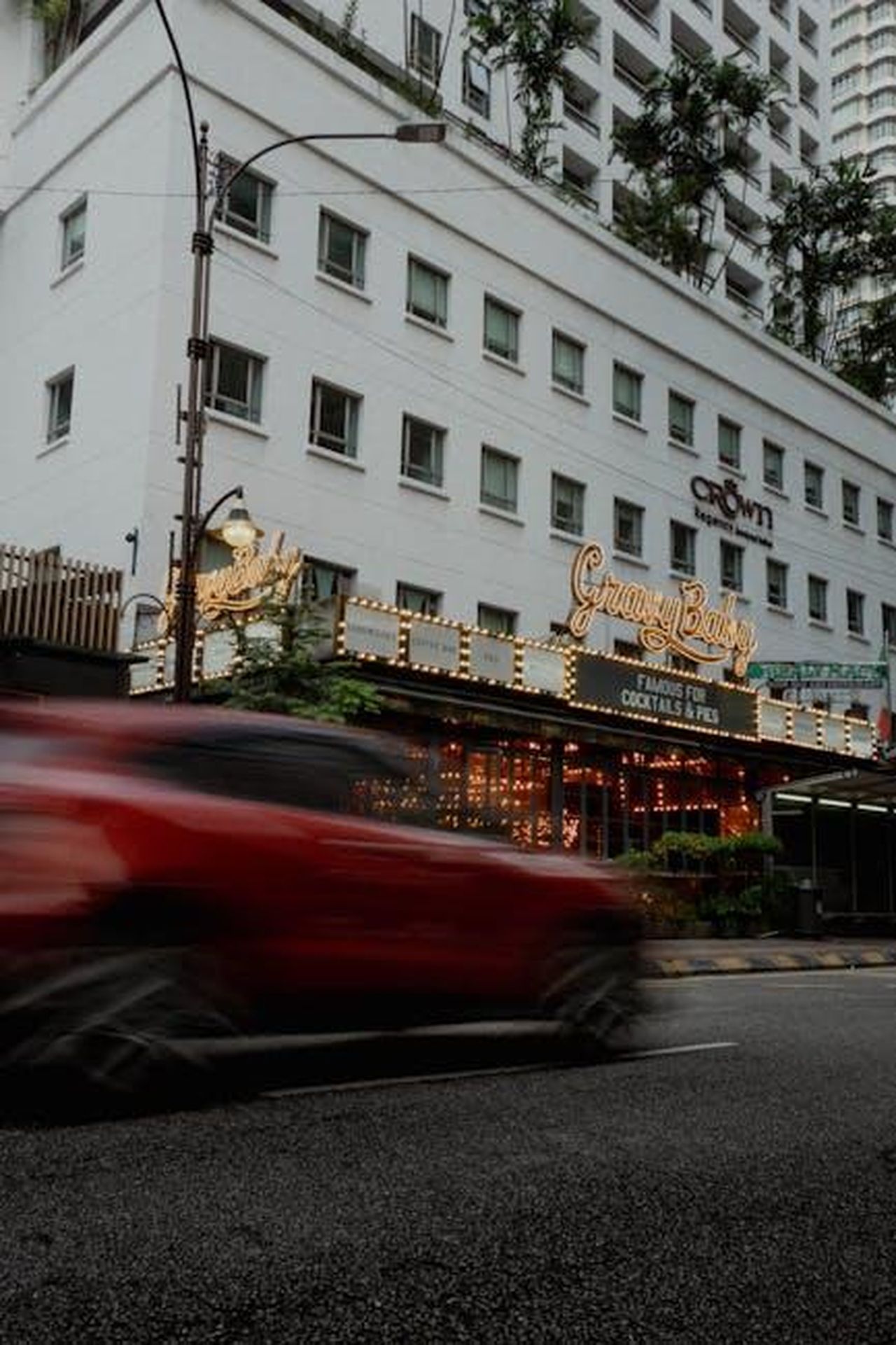 Affrontare_i_Chasers_4RFLLbNqGL - Confidenze24 Source: Iurii Laimin - pexels - Blurred red car speeding past a lively urban city street with illuminated restaurant signs.