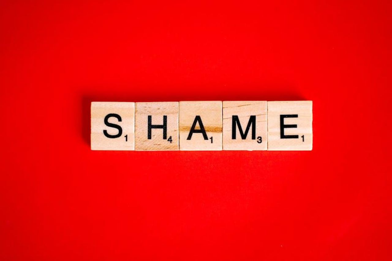 Amanda_Mealing_si_dice_profondamente_vergognosa_enFYF7NRtR - Confidenze24 Source: Anna Tarazevich - pexels - Scrabble tiles spelling the word 'Shame' on a vibrant red backdrop.