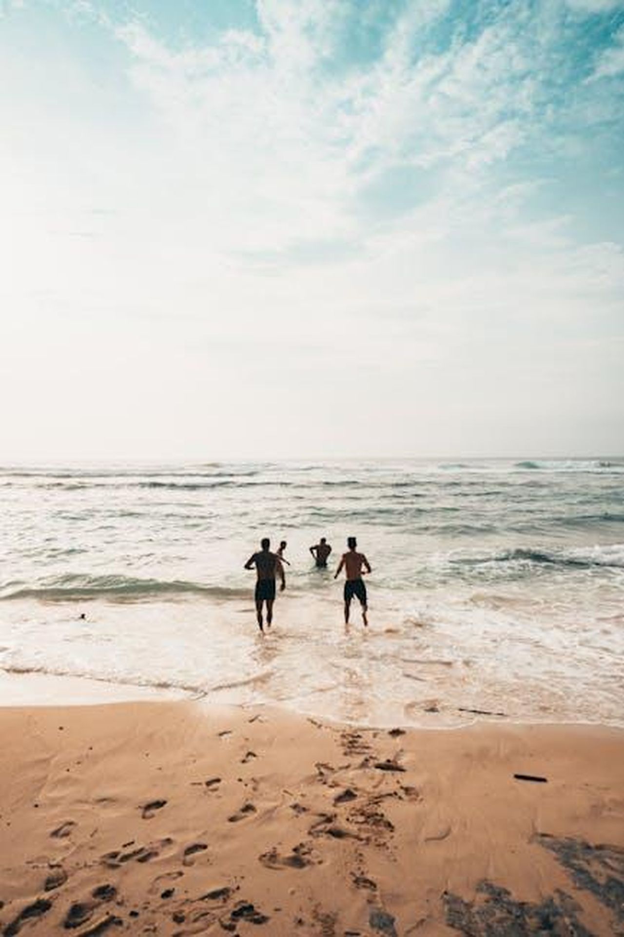 Amici_di_Breonna_condividono_i_loro_ricordi_DdeatH0qxb - Confidenze24 Source: Oliver Sjöström - pexels - Three friends run into the ocean on a sunny day at a scenic beach in Bali.