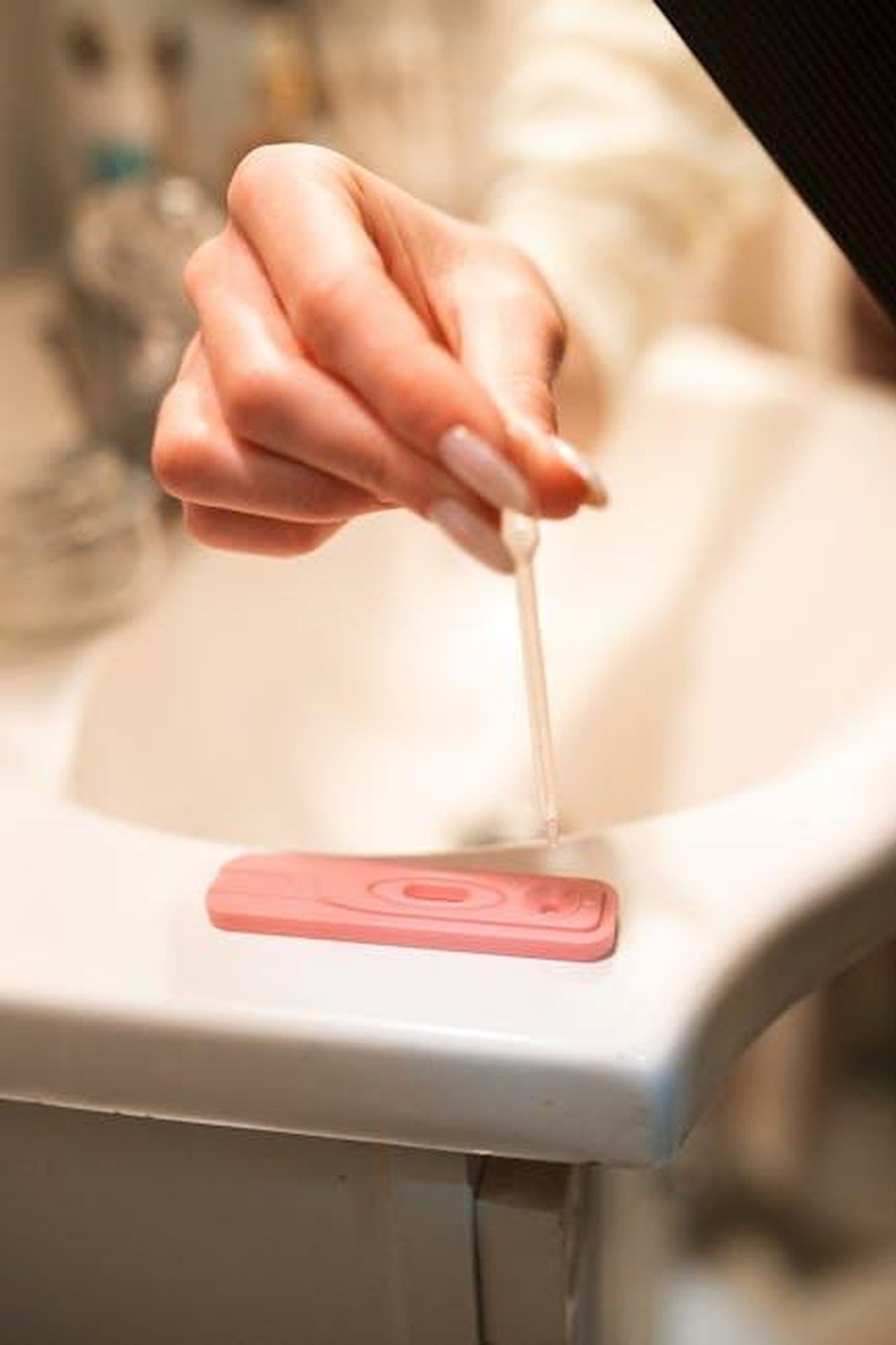 Annuncio_della_gravidanza_wtLV2AyC5n - Confidenze24 Source: RDNE Stock project - pexels - A hand using a pipette on a pregnancy test kit in a bathroom setting.