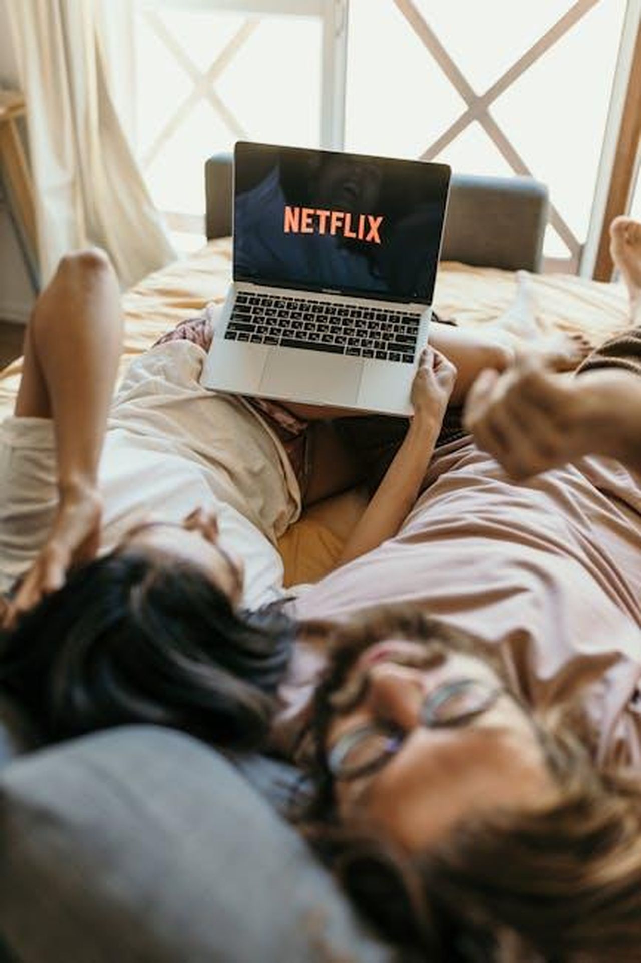 Annuncio_della_seconda_stagione_DiR9DKIXlN - Confidenze24 Source: Anastasia Shuraeva - pexels - Couple relaxing in bed watching Netflix on a laptop, capturing a cozy moment indoors.