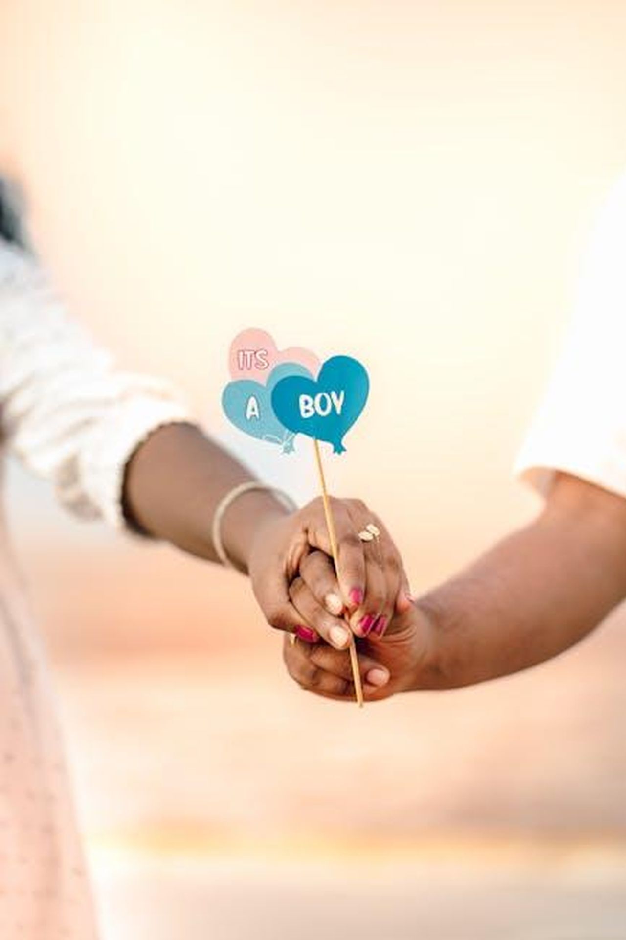 Annuncio_di_Shivon_Zillis_sul_nuovo_bambino_vedUU01ZMk - Confidenze24 Source: Nandhu Kumar - pexels - Joyful couple's hands holding 'It's a Boy' sign, announcing pregnancy on a sunny beach.